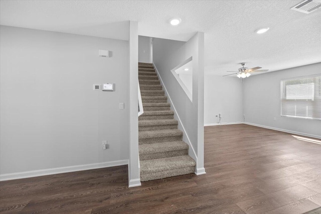 stairs with hardwood / wood-style floors, ceiling fan, and a textured ceiling