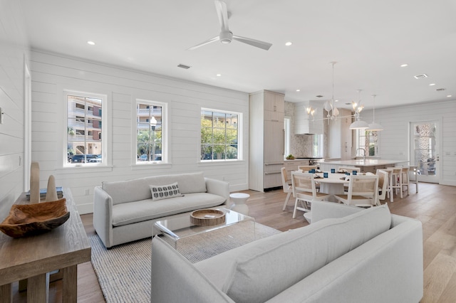 living area with visible vents, ceiling fan with notable chandelier, light wood-style flooring, and recessed lighting