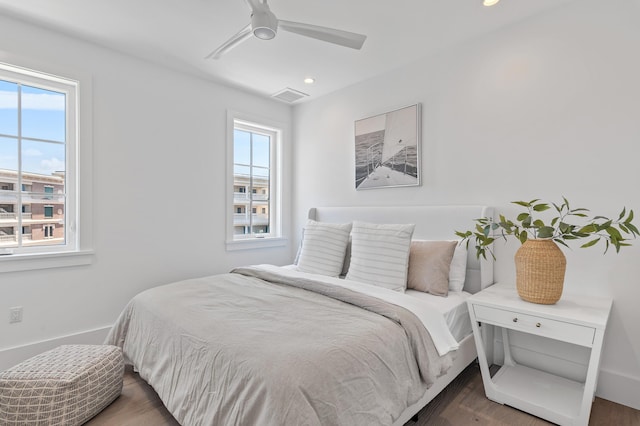 bedroom with multiple windows, dark hardwood / wood-style flooring, and ceiling fan