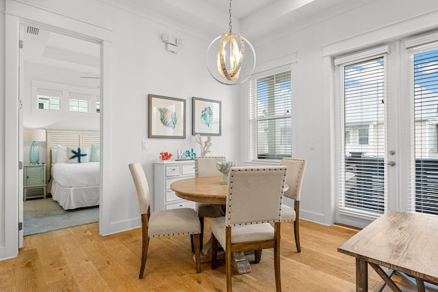 dining area featuring a tray ceiling, light hardwood / wood-style floors, and a healthy amount of sunlight