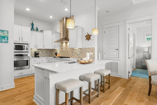 kitchen featuring wall chimney exhaust hood, white cabinetry, and stainless steel appliances