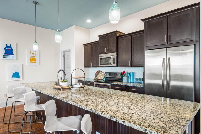 kitchen featuring appliances with stainless steel finishes, decorative light fixtures, backsplash, and dark hardwood / wood-style flooring