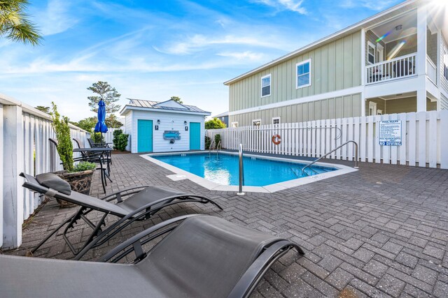 view of swimming pool featuring a patio and an outbuilding