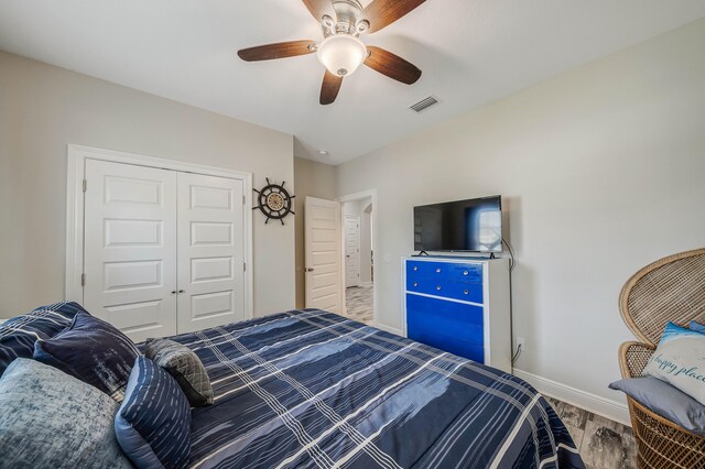 bedroom with wood-type flooring, ceiling fan, and a closet