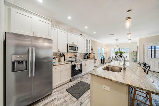 kitchen with stainless steel appliances, white cabinetry, decorative light fixtures, and sink