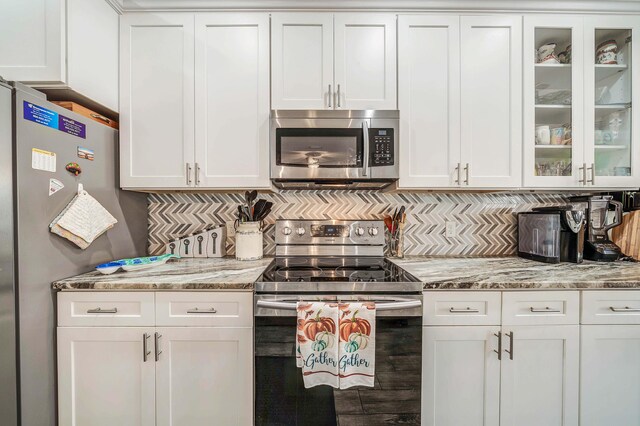 kitchen featuring tasteful backsplash, white cabinetry, stainless steel appliances, and light stone counters