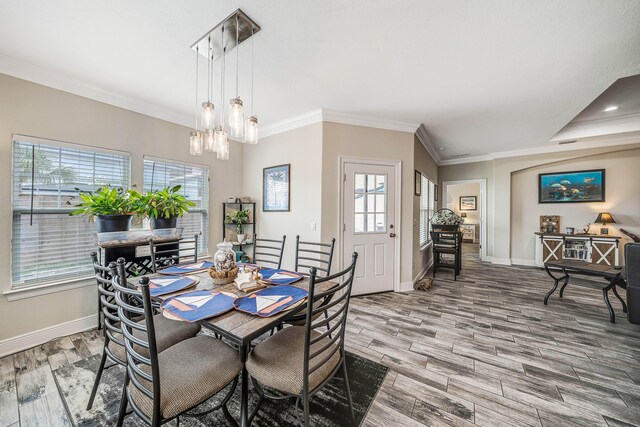 dining space with ornamental molding, a wealth of natural light, wood-type flooring, and an inviting chandelier