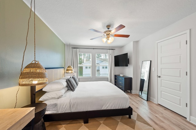 bedroom featuring light hardwood / wood-style floors, ceiling fan, and a textured ceiling