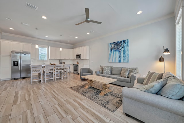 living room with light hardwood / wood-style flooring, ceiling fan, and crown molding