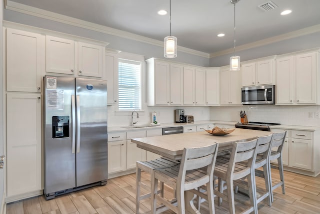 kitchen with appliances with stainless steel finishes, white cabinetry, sink, and decorative light fixtures