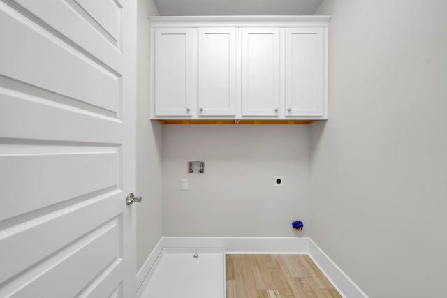 laundry area with washer hookup, electric dryer hookup, light hardwood / wood-style flooring, and cabinets