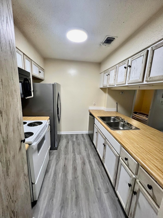 kitchen with white electric range oven, sink, a textured ceiling, light hardwood / wood-style flooring, and dishwasher