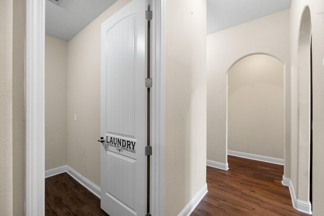 hallway with a textured ceiling and dark hardwood / wood-style flooring