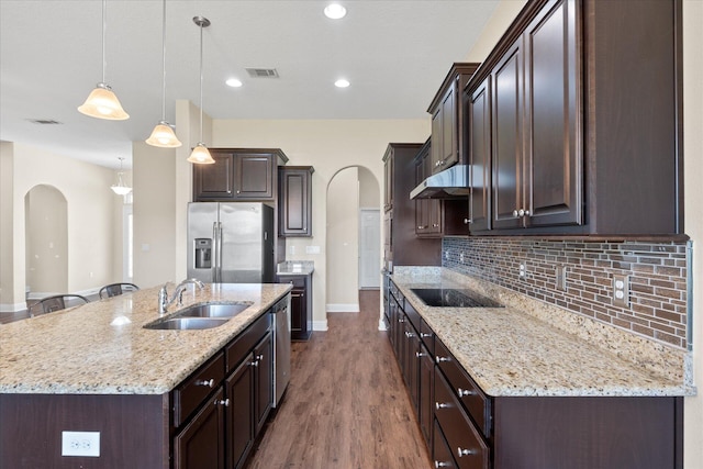 kitchen featuring appliances with stainless steel finishes, pendant lighting, a kitchen island with sink, hardwood / wood-style floors, and sink