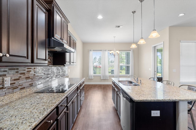 kitchen featuring sink, stainless steel dishwasher, a center island with sink, backsplash, and a breakfast bar area