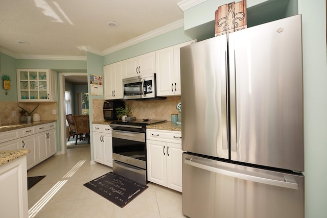 kitchen with light stone counters, white cabinets, backsplash, appliances with stainless steel finishes, and light tile patterned floors