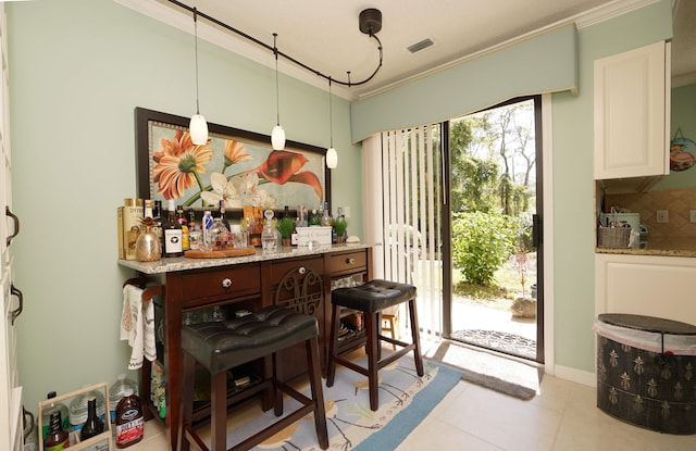 tiled dining space with crown molding and bar area