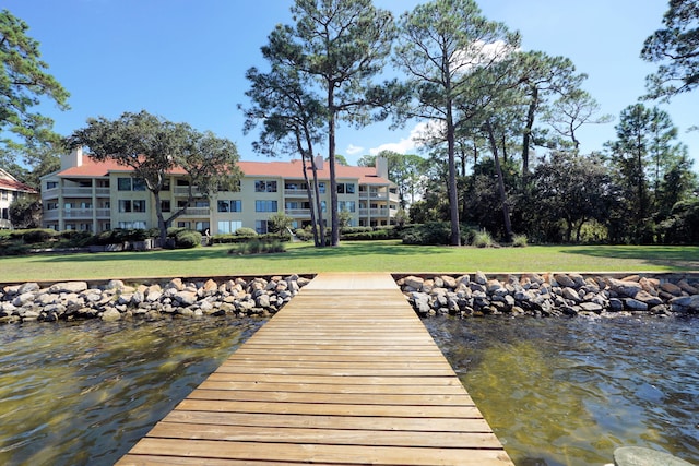 dock area with a lawn and a water view