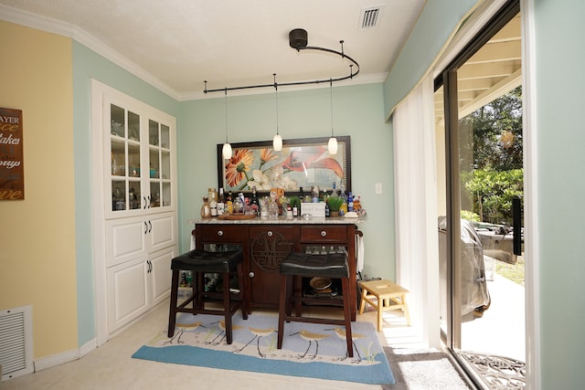 dining room with bar area, a textured ceiling, and crown molding