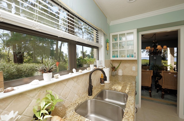 kitchen featuring sink, backsplash, tile patterned floors, a notable chandelier, and crown molding