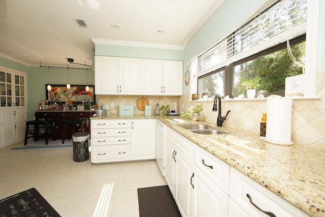 kitchen featuring light stone countertops, decorative backsplash, sink, and white cabinets