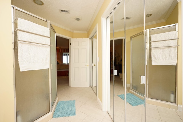 bathroom with a textured ceiling, tile patterned flooring, ornamental molding, and a shower with shower door