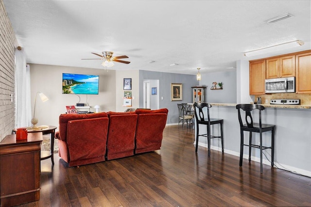 living room featuring dark wood-type flooring, ceiling fan, a textured ceiling, and a fireplace