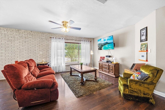 living room with dark hardwood / wood-style flooring, a textured ceiling, brick wall, and ceiling fan