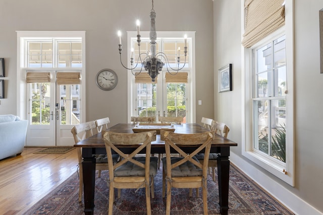 dining area featuring wood-type flooring, an inviting chandelier, and french doors