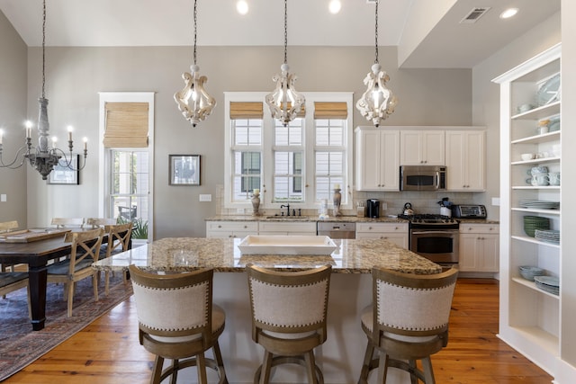 kitchen with stainless steel appliances, white cabinetry, a center island, and light wood-type flooring