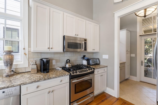 kitchen featuring a healthy amount of sunlight, white cabinetry, decorative backsplash, and stainless steel appliances