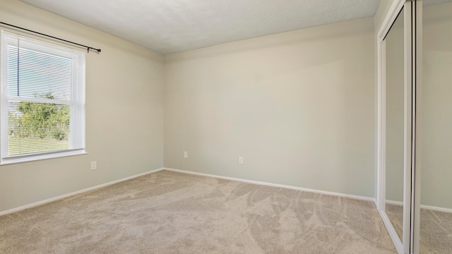 unfurnished bedroom with light colored carpet and multiple windows