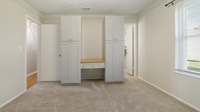 unfurnished bedroom featuring a textured ceiling and light colored carpet