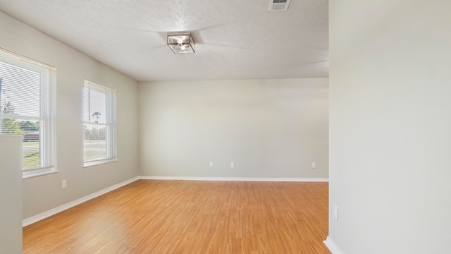 unfurnished room featuring light hardwood / wood-style floors and a textured ceiling