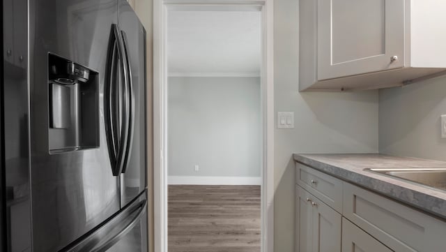 kitchen featuring light wood-type flooring, white cabinets, crown molding, and stainless steel fridge