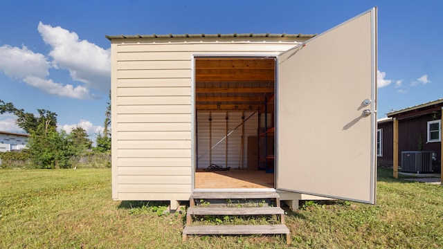 view of outbuilding with central AC unit and a lawn