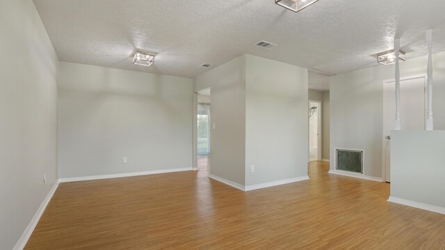 spare room featuring a textured ceiling and light hardwood / wood-style floors