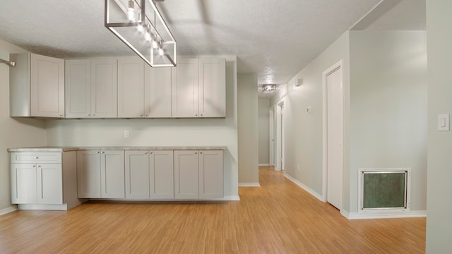 kitchen featuring light wood-type flooring, a textured ceiling, and white cabinetry