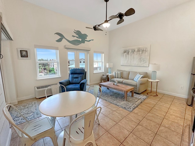 living room with a towering ceiling, ceiling fan, a healthy amount of sunlight, and light tile patterned floors