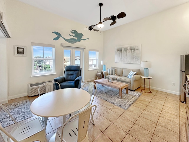 living room featuring ceiling fan, a towering ceiling, light tile patterned floors, and a wall unit AC