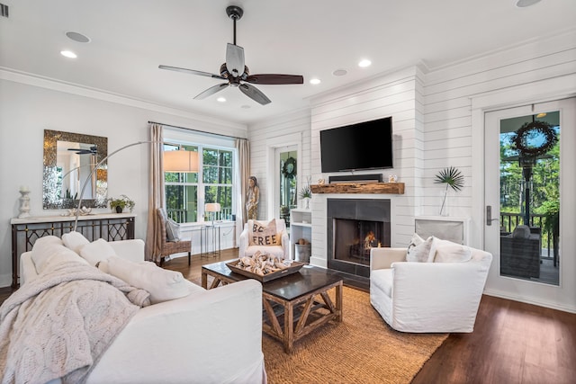 living room featuring ceiling fan, ornamental molding, and dark wood-type flooring