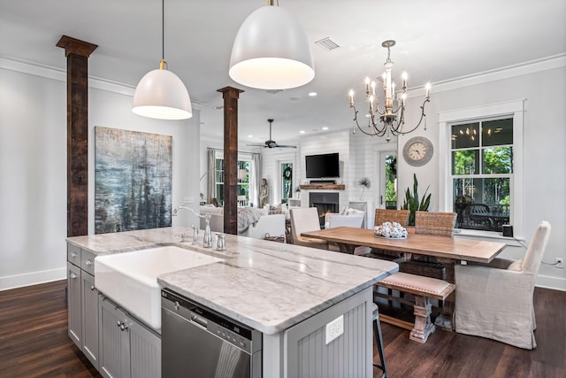 kitchen featuring stainless steel dishwasher, gray cabinets, hanging light fixtures, and decorative columns