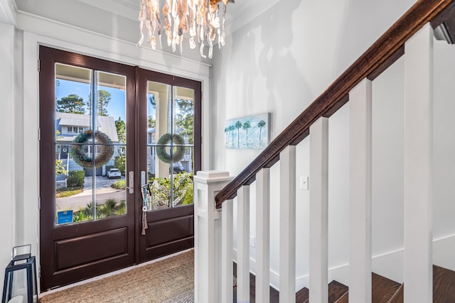 carpeted entrance foyer featuring french doors and a chandelier