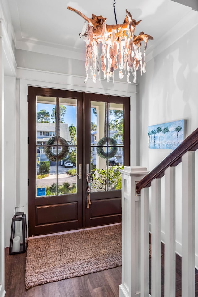 foyer entrance with dark hardwood / wood-style flooring, french doors, an inviting chandelier, and ornamental molding