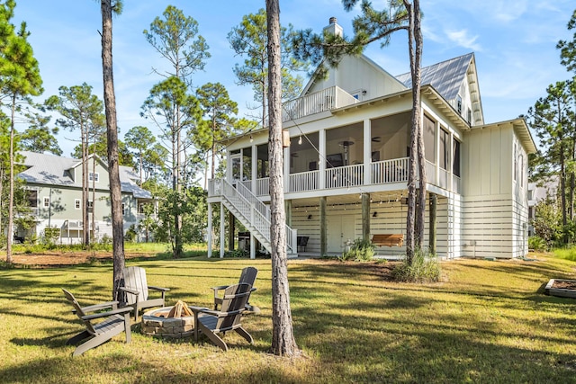 back of property with a yard, an outdoor fire pit, and a sunroom