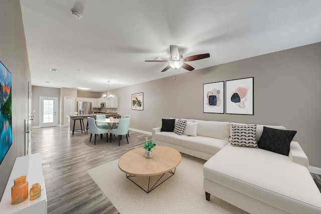 living room with ceiling fan with notable chandelier and wood-type flooring