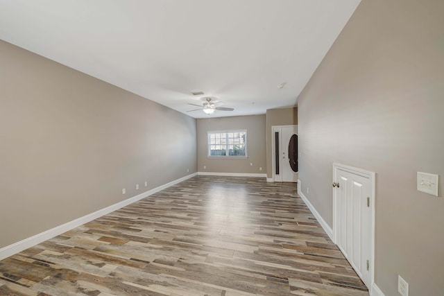spare room featuring baseboards, wood finished floors, and ceiling fan