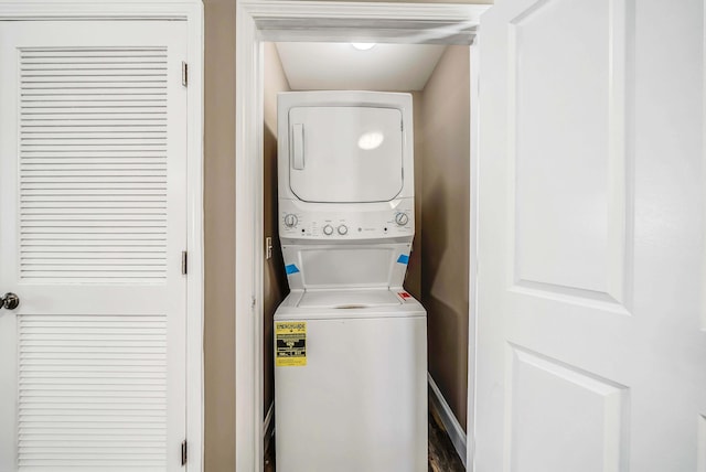 laundry area with baseboards, stacked washer and clothes dryer, and laundry area