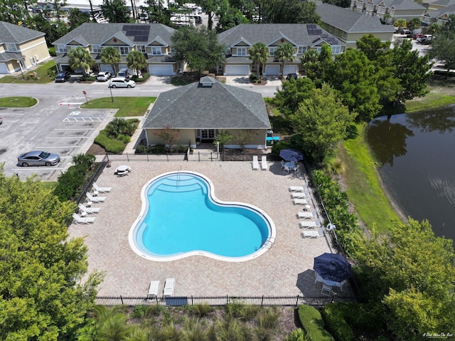 community pool featuring fence, a water view, and a residential view