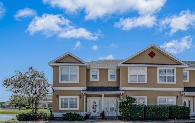 townhome / multi-family property with a shingled roof and stucco siding